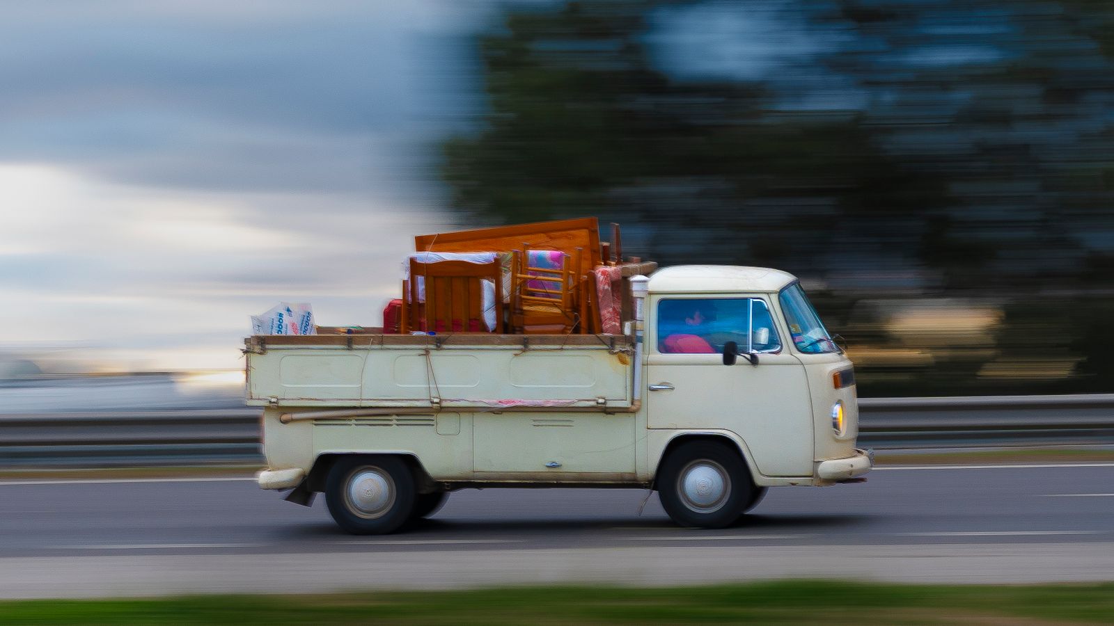 A loaded moving van hauling furniture and household items on the highway — representing fast residential junk removal and haul-away service.